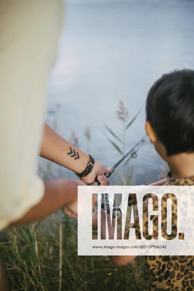 IMAGO Creative, Jahreszeit Sommer, Sommerferien Cropped hand of father and daughter fishing in lake during summer, MA83054, Sweden, Stockholm, model released