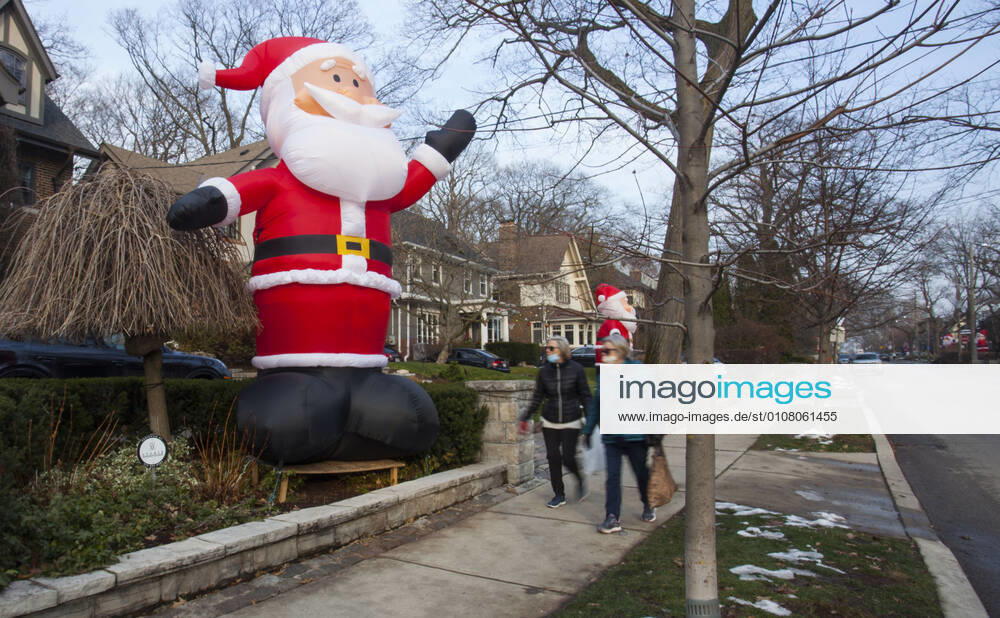 (201212) -- TORONTO, Dec. 12, 2020 -- People wearing face masks walk past a giant-sized inflatable Santa Claus on Inglewood Drive in Toronto, Canada, Dec. 11, 2020. Starting from 2013, dozens of inflatable 14-foot-high Santa Clauses stretch along Inglewood Drive in Toronto during the holiday season, attracting lots of visitors. (Photo by Xinhua) CANADA-TORONTO-CHRISTMAS DECORATION-INFLATABLE SANTA CLAUSES ZouxZheng