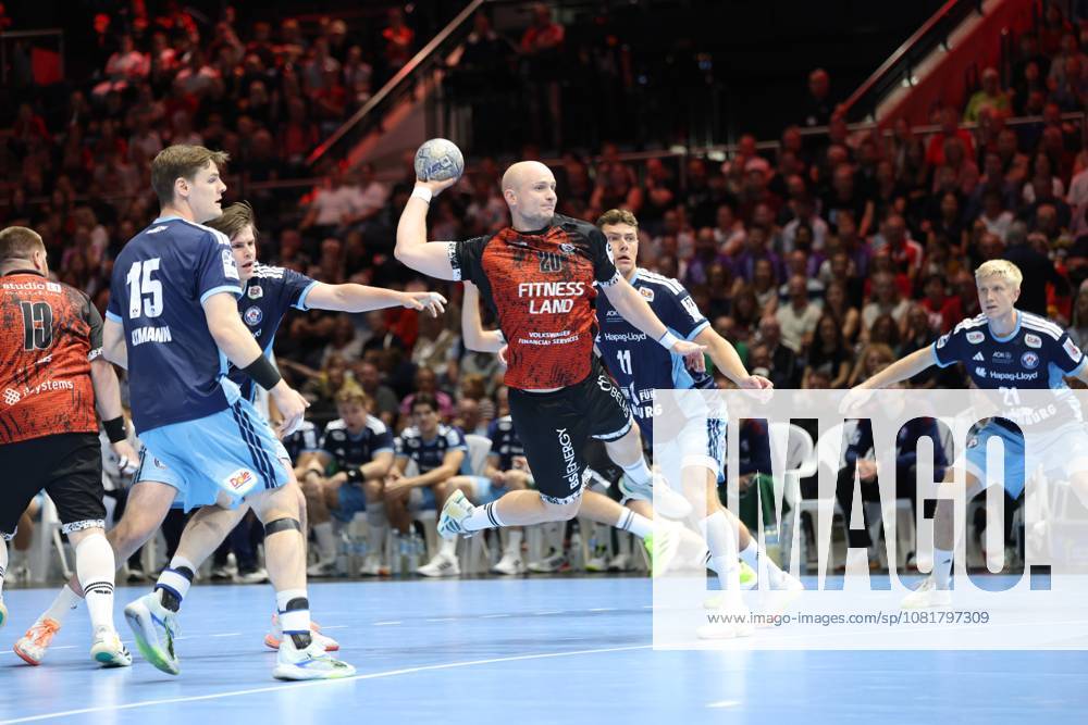 Melf Hagen 20 of MTV Braunschweig rises for a jump shot at the Volkswagen Halle in Braunschweig, surrounded by Dominik Axmann 15 of HSV Hamburg, Nicolaj Jørgensen 11 of HSV Hamburg, and Frederik Bo Andersen 21 of HSV Hamburg. The Hamburg defense tries to block the shot, while the crowd watches the action up close. Melf Hagen 20 of MTV Braunschweig attempts a jump shot against HSV Hamburg.
