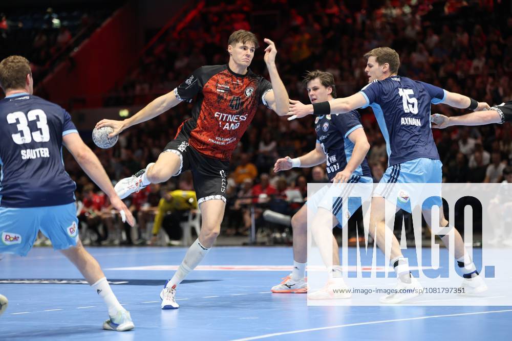Rick Harder of MTV Braunschweig breaks through the HSV Hamburg defense while jumping with the ball, including Dominik Axmann (15) and Moritz Sauter (33). The scene shows a dynamic offensive drive in the packed Volkswagen Halle in Braunschweig. Rick Harder (40) of MTV Braunschweig breaks through against HSV Hamburg.