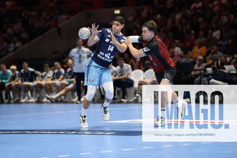Mahmoud El Shobaky, No. 14, of HSV Hamburg, is pulling away for a shot while being pressured by a player from MTV Braunschweig. The ball is already in flight, the scene shows intense physical play at the Volkswagen Halle in Braunschweig. Mahmoud El Shobaky (14) of HSV Hamburg is locked in a battle for the ball as he attempts a shot