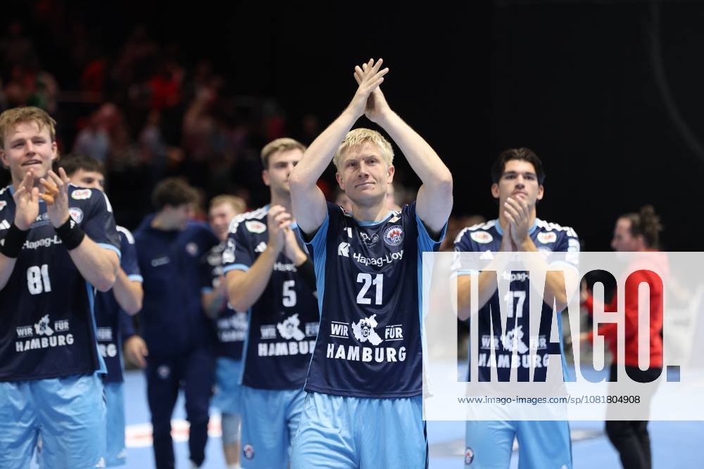 Frederik Bo Andersen, 21, of HSV Hamburg, applauds with his hands raised toward the fans, flanked by Martin Hovde 81 of HSV Hamburg and Kaj Geenen 17 of HSV Hamburg. The entire team celebrates together at the Volkswagen Halle in Braunschweig. Frederik Bo Andersen 21 of HSV Hamburg celebrates with the team.