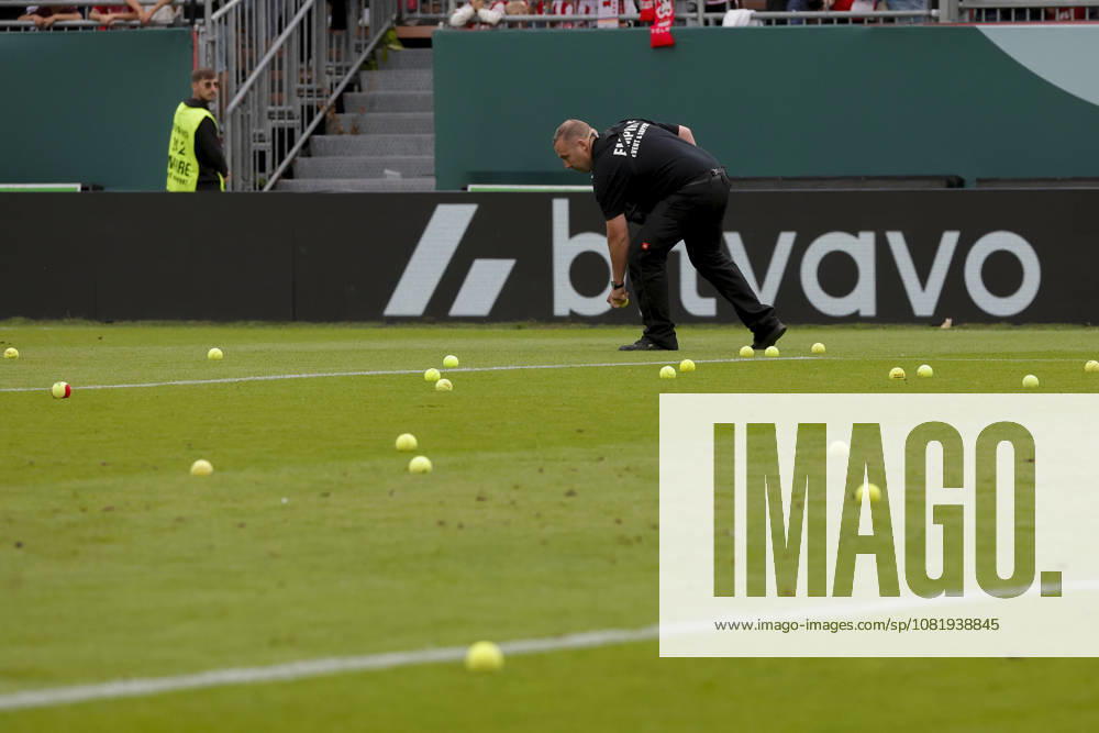In the photo, fans are throwing tennis balls onto the field in protest; security guards are forced to pick them up; game interruption on August 24, 2026, FC Würzburger Kickers vs. FC Köln, DFB Cup, First Round, Germany, Würzburg, AKON Arena, DFL REGULATIONS PROHIBIT ANY USE OF PHOTOGRAPHS AS IMAGE SEQUENCES AND OR QUASI-VIDEO