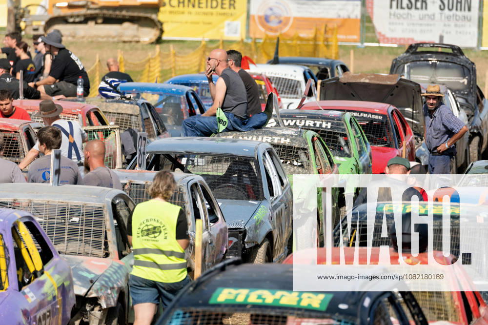 Numerous drivers and volunteers among the heavily battered stock cars in the paddock at the FUN CROSS stock car race near Dietenwengen. The tightly packed race cars clearly show the marks left by previous races. FUN CROSS stock car race in Eberhardzell. Eberhardzell, Dietenwengen