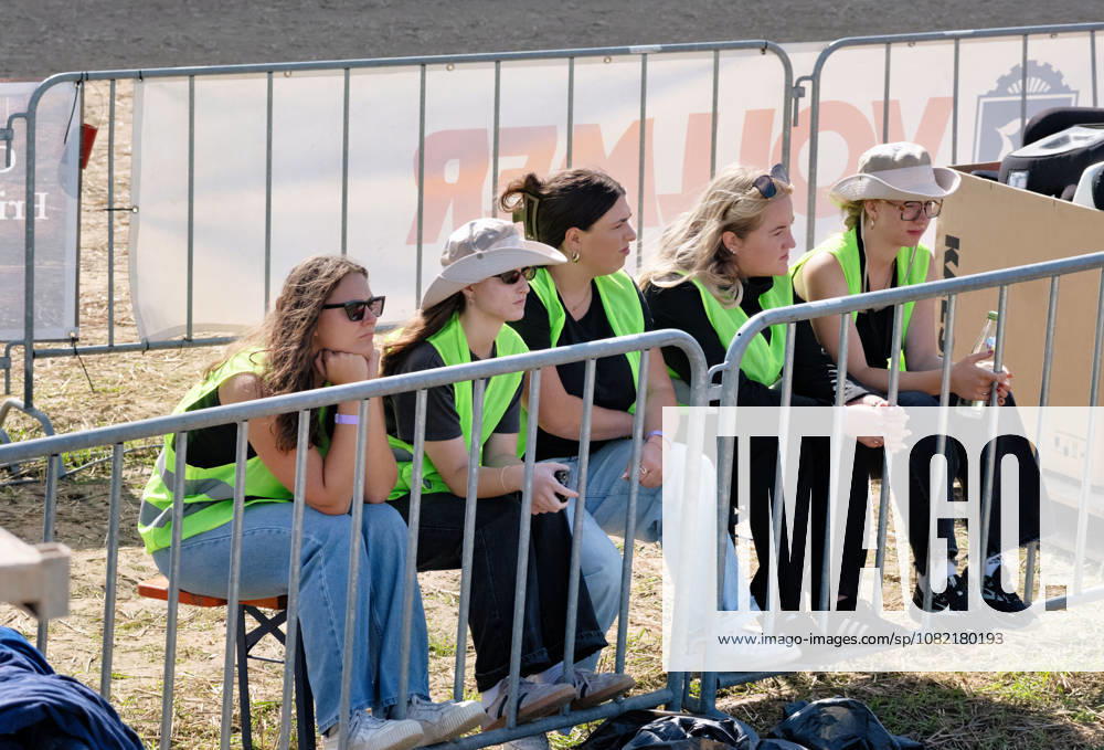 Several female volunteers watch the action at the FUN CROSS stock car race near Dietenwengen. The women, wearing high-visibility vests, are seated right next to the roped-off track area at the FUN CROSS stock car race in Eberhardzell. Eberhardzell, Dietenwengen