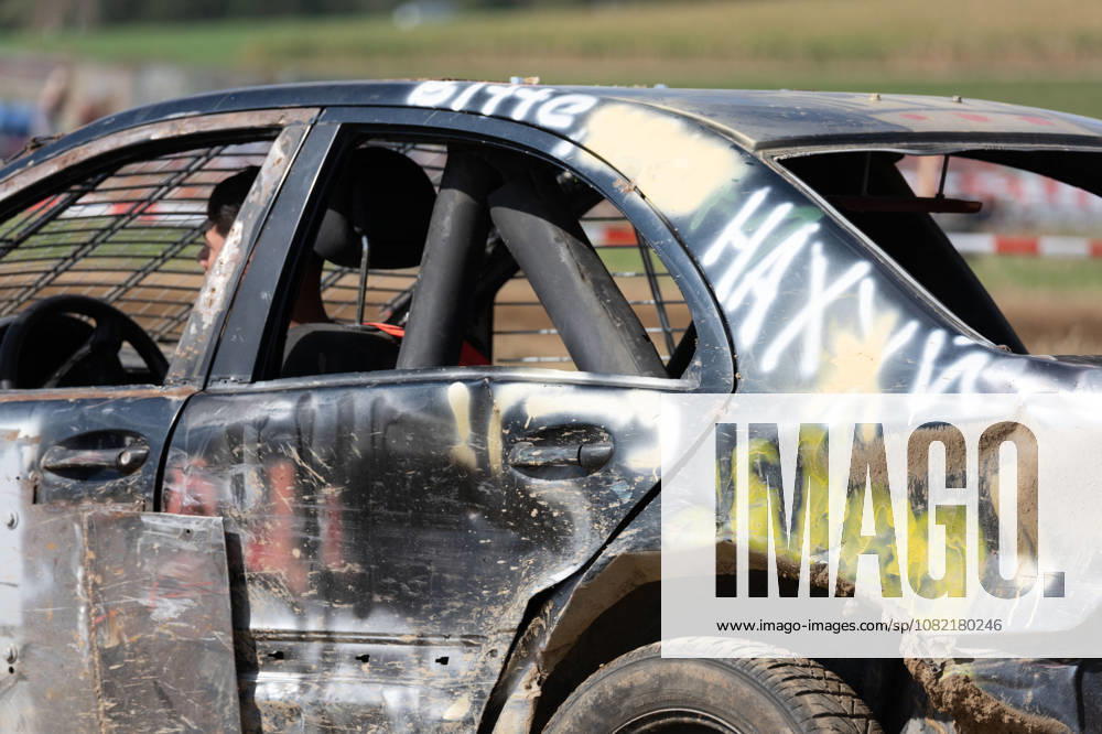 Close-up of a heavily battered stock car at the FUN CROSS stock car race near Dietenwengen. The scratched and dirty bodywork, spray-painted lettering, and the visible roll cage highlight the rough-and-tumble nature of the races. FUN CROSS Stock Car Races in Eberhardzell. Eberhardzell, Dietenwengen