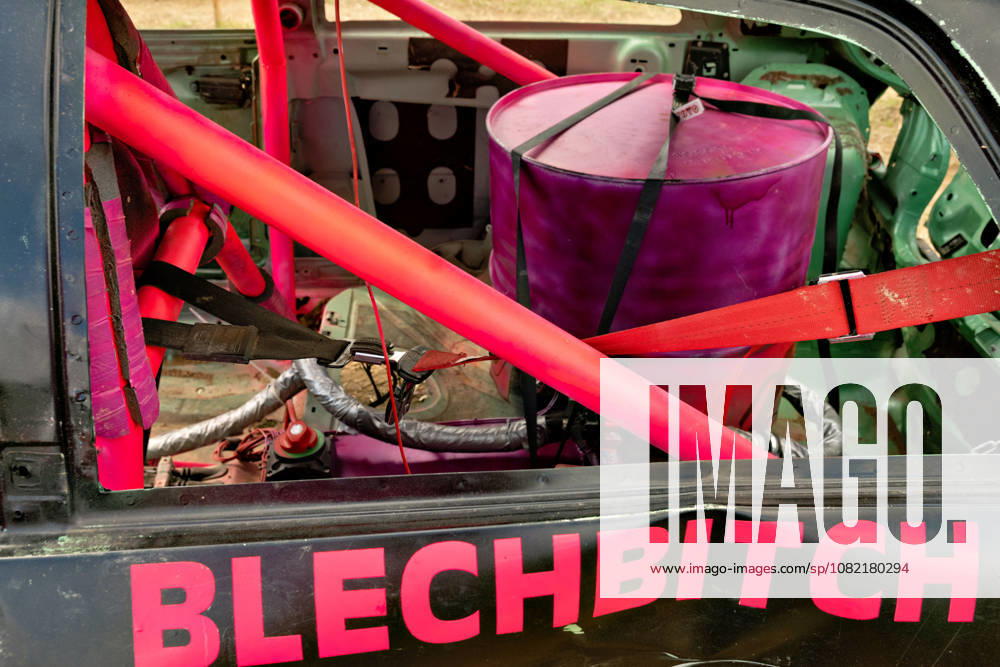 Close-up of a modified stock car at the FUN CROSS stock car race near Dietenwengen. Inside the stripped-down cabin, you can see the pink roll cage, safety belts, and a secured metal barrel. The Blechbitch lettering on the side of the vehicle is particularly eye-catching. FUN CROSS stock car race in Eberhardzell. Eberhardzell, Dietenwengen