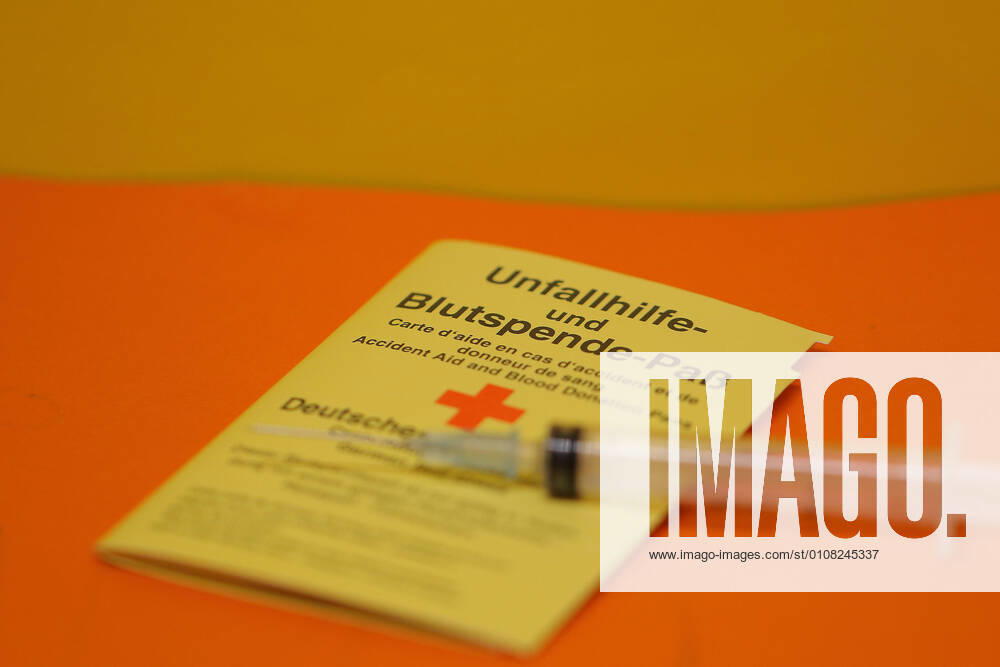 Frankenberg, Germany 13 December 2020 A passport for accident assistance and blood donation lies on an orange background, on the blood donation passport lies a syringe Hessen