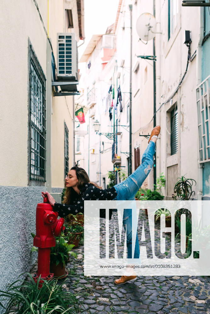 Young slim casual woman stretching on street of old city while dancing gracefully, Model released