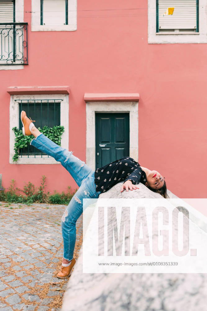 Young slim casual woman stretching on street of old city while dancing gracefully, Model released