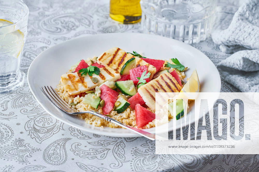 Appetizing Bulgur salad with watermelon and cucumbers in plate served on table for tasty lunch