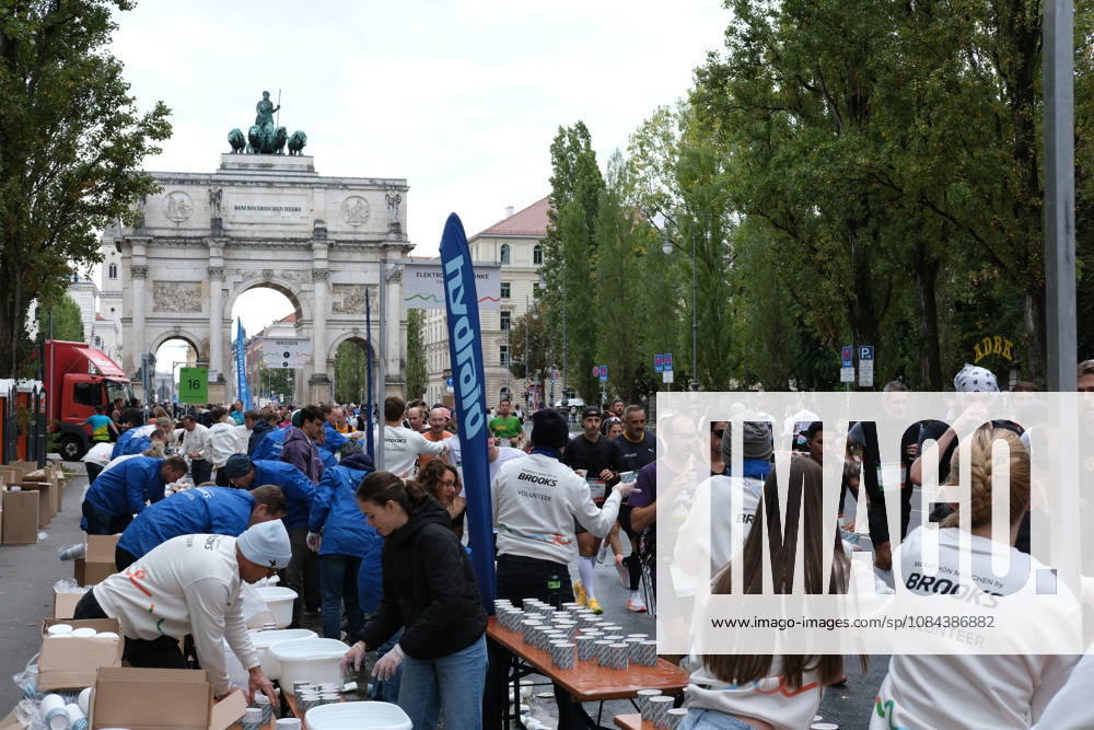 Munich Marathon 2026 MUNICH, GERMANY - OCTOBER 11: Volunteers prepare and hand out cups of water at a refreshment station near the Siegestor victory arch during the 2026 Munich Marathon in Munich, Germany on October 11, 2026. Runners pass through the station as volunteers in Brooks Marathon München shirts line the tables. Merve Goettl Anadolu Munih Germany. Editorial use only. Please get in touch for any other usage.
