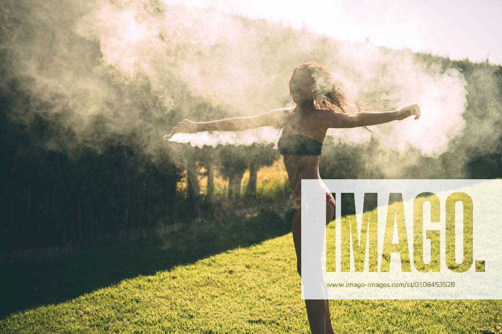 Pretty girl wearing swimsuit posing with smoke torch on pool party in yard., Model released, Property released