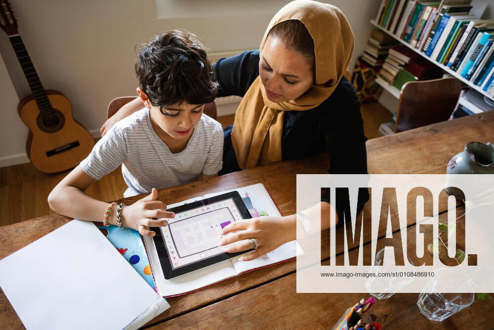 IMAGO Creative: Bildung, Musikerziehung High angle view of mother assisting son in using digital tablet while studying at home , model released, property released