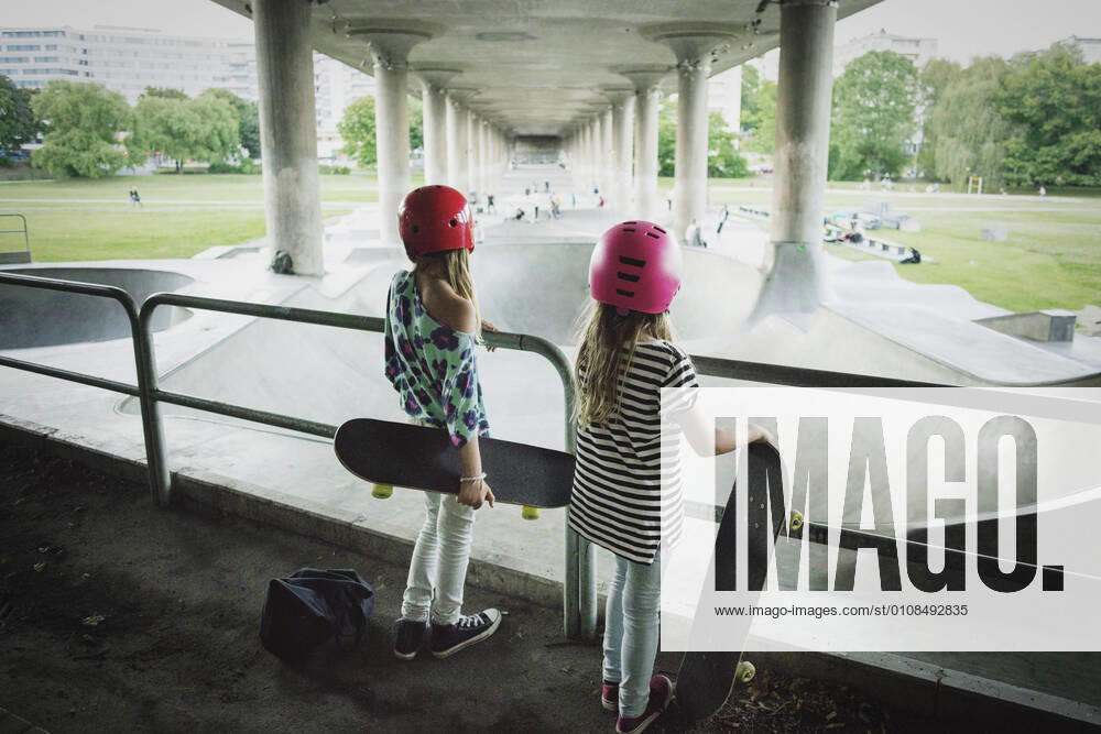 Rear view of friends looking at skateboard park while standing by railing , model released