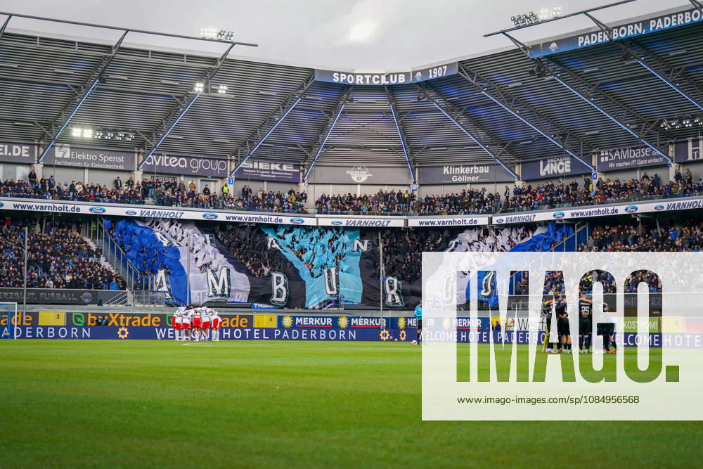 Germany Soccer Bundesliga 2026–2027, Matchday 7: SC Paderborn vs. Hamburger SV at Home Deluxe Arena in Paderborn. Wide shot of the Home Deluxe Arena in Paderborn; interior view featuring a large blue, black, and white choreographed display by SC Paderborn 07 home fans in the stands; HAMBURG fan choreography; Ultras, fan scene, spectators, flags, fan section, atmosphere, pre-game huddles for both teams, Hamburger SV, HSV, SC Paderborn, soccer, Bundesliga, sports venue, stadium roof, floodlights, playing field, sponsors, advertising, advertising banners, Merkur, buXtrade, Varnholt, Welcome Hotel