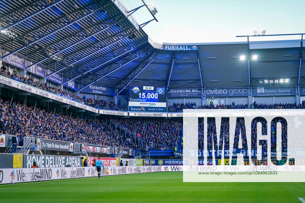 Germany Soccer Bundesliga 2026–2027, Matchday 7: SC Paderborn vs. Hamburger SV at Home Deluxe Arena, Paderborn. Wide shot of the Home Deluxe Arena in Paderborn; interior view with packed stands and stadium scoreboard. 15,000 spectators at the Bundesliga match between SC Paderborn 07 and Hamburger SV (HSV). Sold-out stadium, Attendance, fans, fan section, stadium roof, floodlights, playing field, assistant referee, scoreboard, sports venue, soccer, Bundesliga, advertising, sponsors, advertising banners, WestfalenWIND, Merkur, buXtrade, avitea group, Klinkerbau Göllner