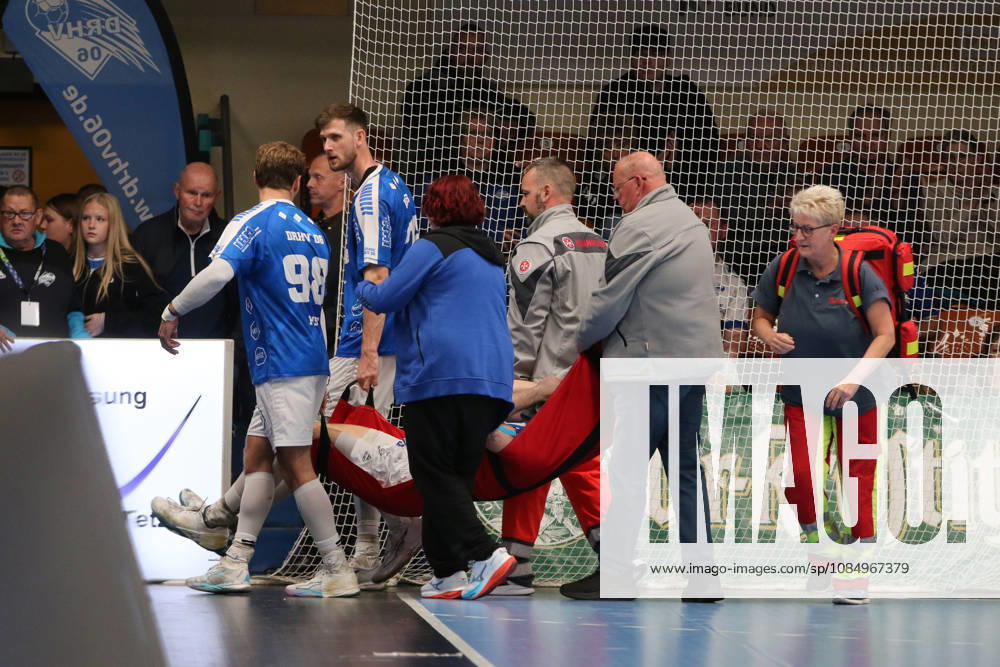 Men s Handball 2026–2027, 2nd Division, Matchday 9: Dessau Roßlauer HV 06 vs. SC DHfK Leipzig at Anhalt Arena, Dessau; Marcel Nowak, Dessau, 15, blue, is carried out of the arena by the emergency physician, first responders, and Yannick Danneberg, Dessau, 26, blue, as well as Yannick Marcos Pust, Dessau, 98, blue. Dessau-Roßlau, Saxony-Anhalt, Germany
