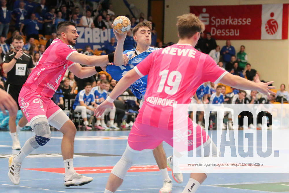 Men s Handball 2026–2027, 2nd Division, Matchday 9: Dessau Roßlauer HV 06 vs. SC DHfK Leipzig at Anhalt Arena, Dessau. Alen Hadzimuhamedovic, Dessau, 11, in blue, passes the ball while being held by Luka Rogan, Leipzig, 33, in pink; Dessau Roßlau, Saxony-Anhalt, Germany
