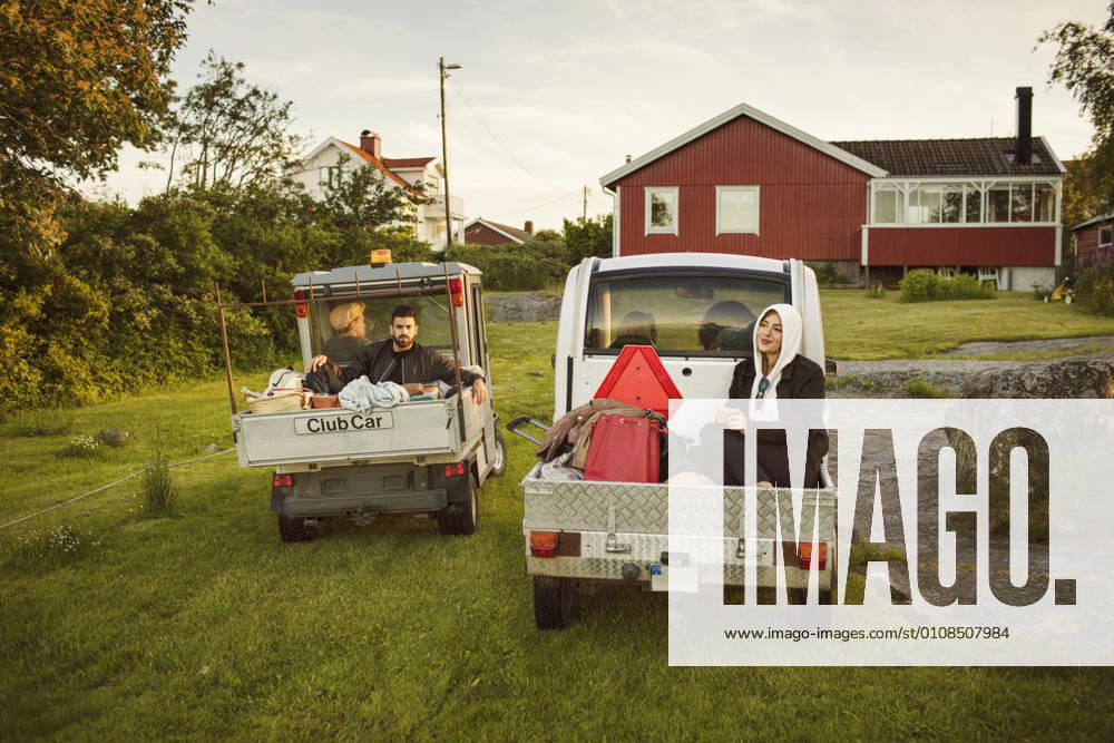 Young friends sitting in vehicles against house , model released