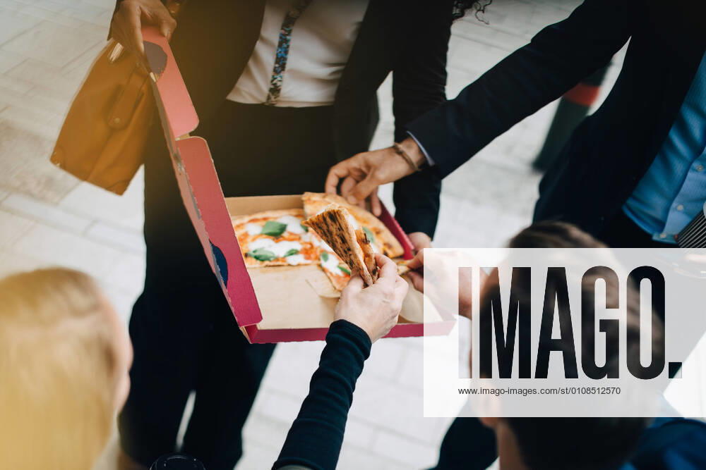 High angle view of business colleagues are eating pizza from box in city , model released