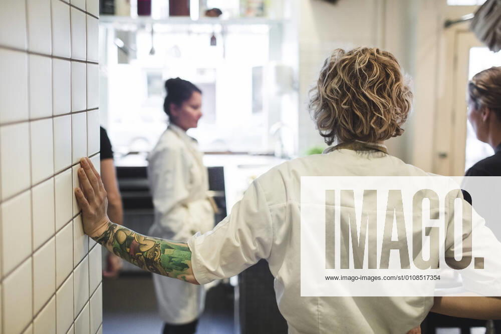 Rear view of chef standing with female colleagues in restaurant kitchen , model released, property released
