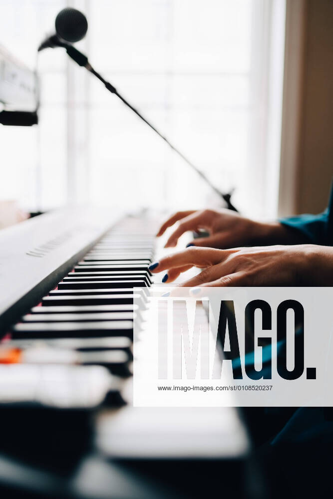 IMAGO Creative: Bildung, Musikerziehung Cropped image of woman playing piano by window at studio , model released, property released