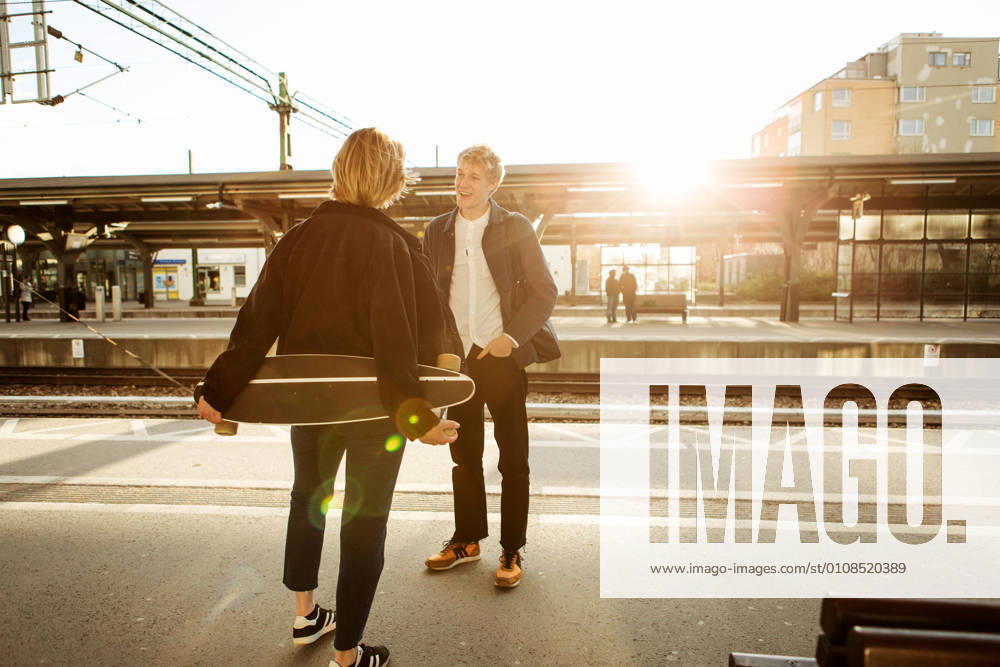 IMAGO Creative, Urban Lifestyle Happy young man talking with teenage girl while standing on railroad station platform , model released