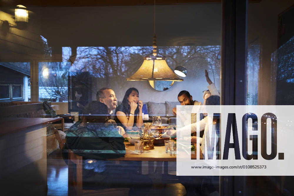 IMAGO Creative: Landleben - Essen Multi-generation family talking while having dinner at table seen through window , model released, property released
