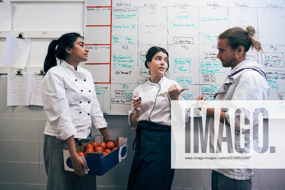 Chefs communicating against whiteboard in kitchen , model released, property released