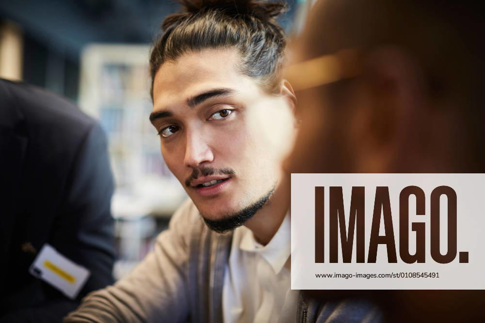 Creative businessman looking at male colleague during meeting in office , model released, property released