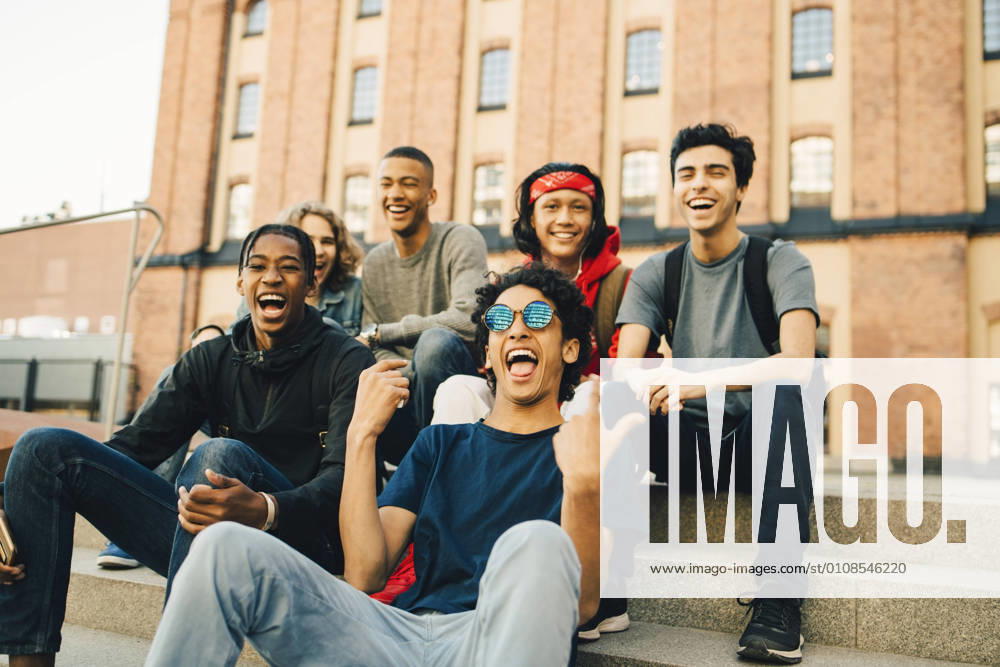Happy male friends sitting in city , model released