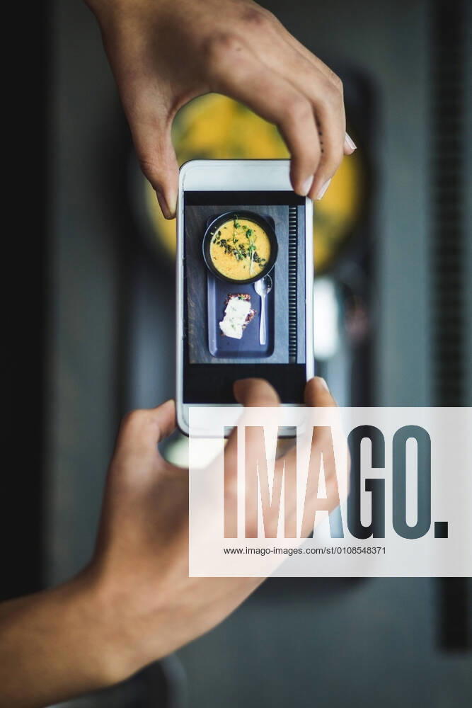 Directly above view of female blogger photographing pumpkin soup and crispbread through smart phone at creative office , model released, property released