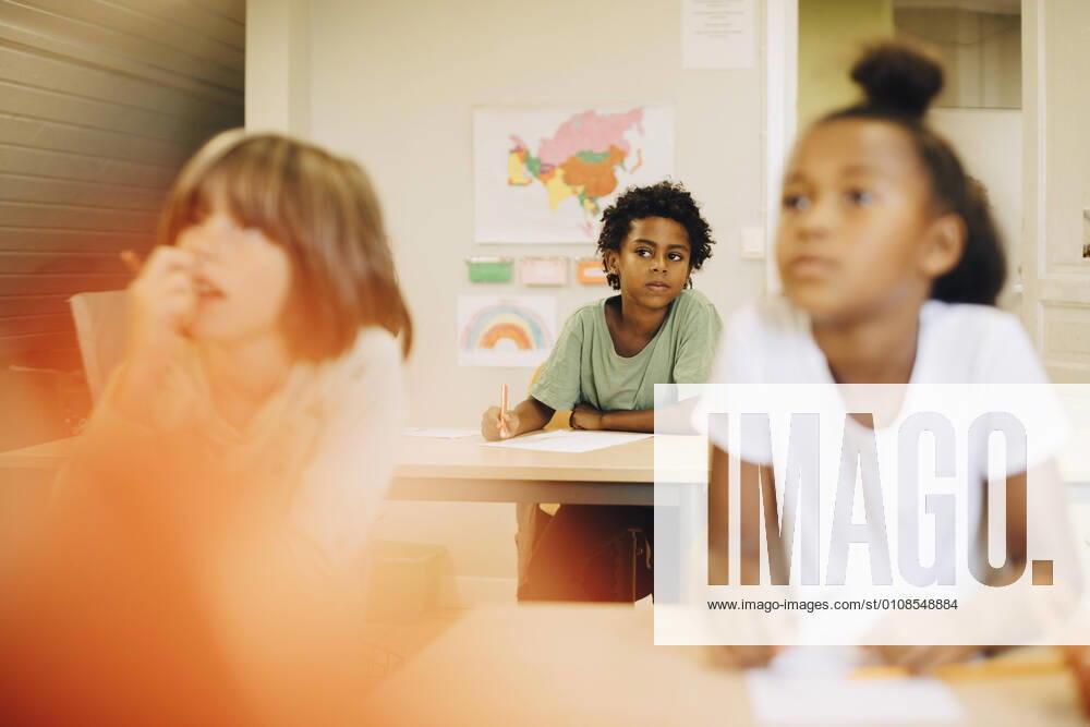 IMAGO Creative: Gesellschaft, Schule, Schulanfang Male and female students sitting at desk in classroom , model released, property released