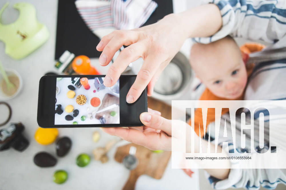 High angle view of female influencer food blogging with baby girl in kitchen , model released, property released