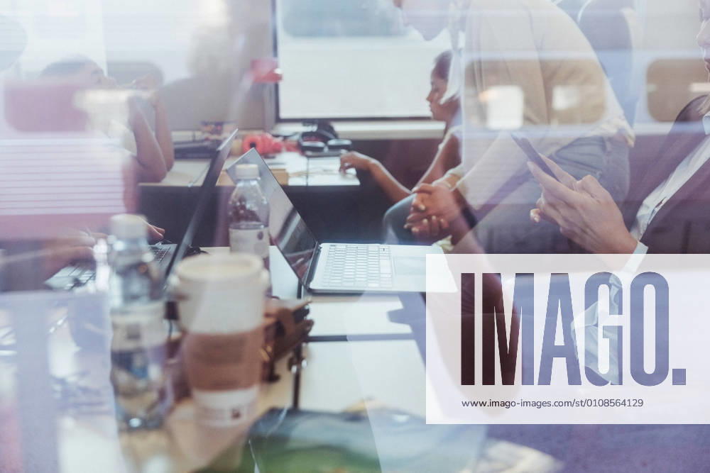 IMAGO Creative: Business, Innovative Technologie-Lösungen Businesswoman using phone with family in background seen through train window , model released, property released