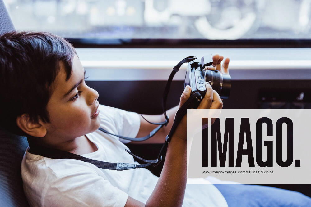 Boy photographing through camera while sitting in train , model released, property released