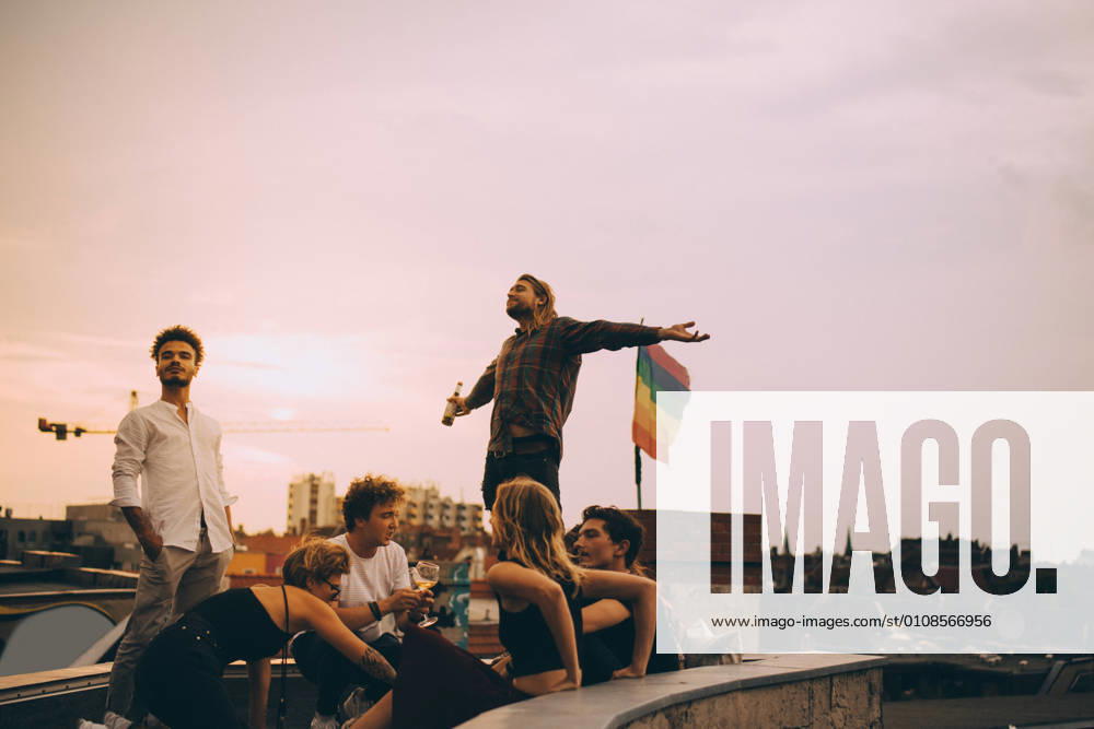 IMAGO Creative, Lifestyle, Leben in einer Wohngemeinschaft, WG IMAGO Kreativ: Urbane Kultur - Sommer auf den Dächern IMAGO Creative: Menschen in Berlin Man enjoying beer while relaxing with friends on terrace at rooftop party , model released, property released