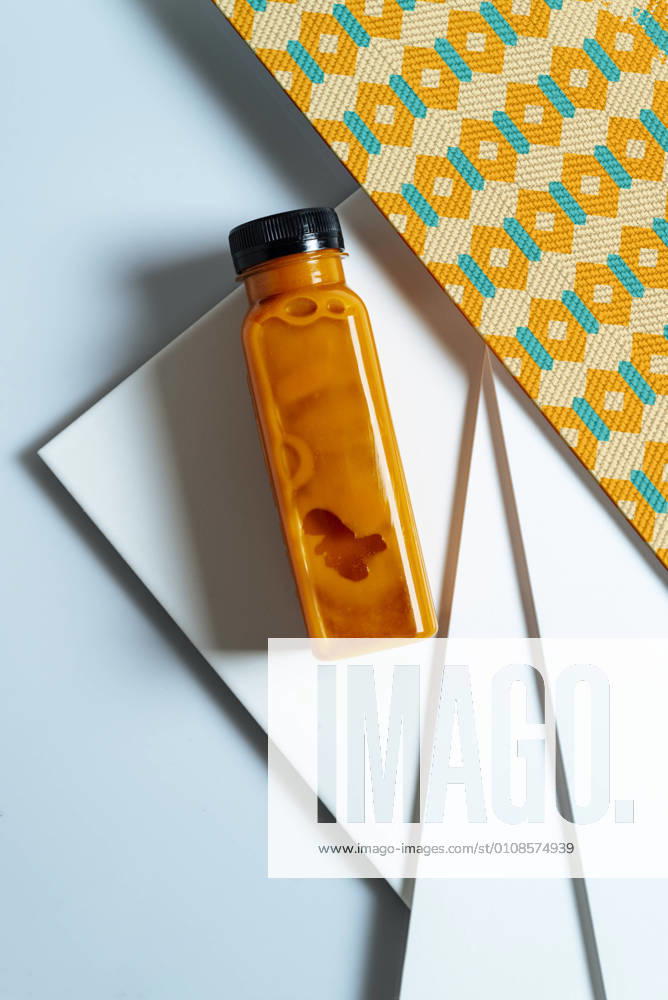 Mango and pumpkin smoothie bottle over retro style geometric textures. From above, Model released, Property released