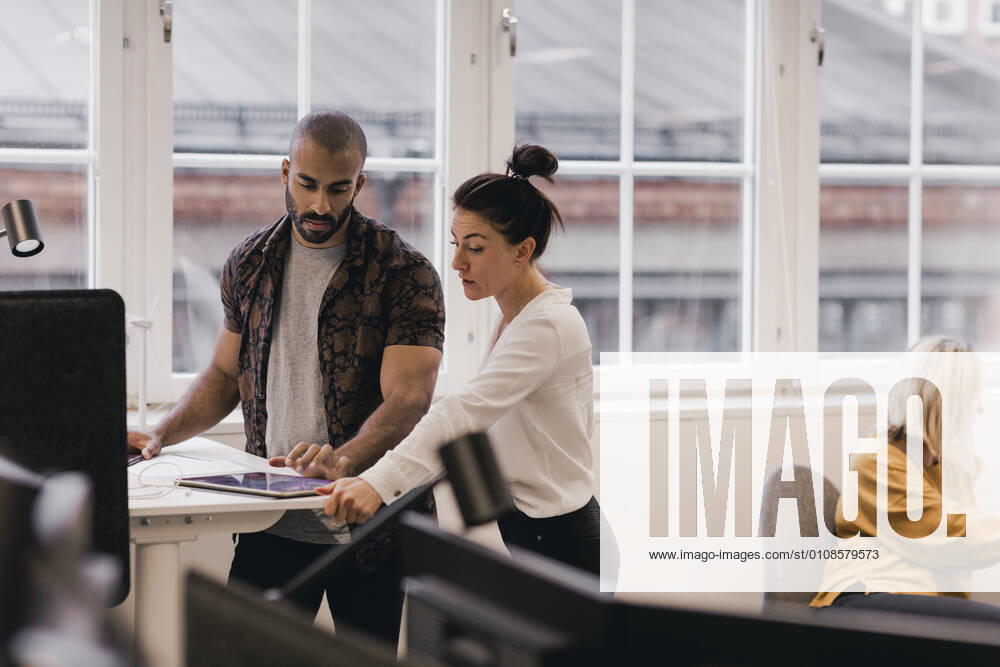 IMAGO Creative: Business, Innovative Technologie-Lösungen Businesswoman discussing with male coworker over digital tablet at office , model released, property released