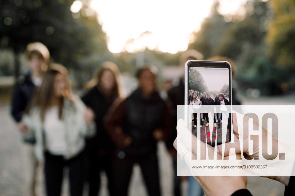 Cropped hands of woman with smart phone filming teenagers dancing on street in city Sweden, Stockholm, model released