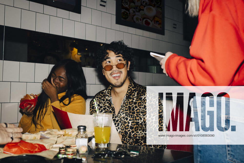 Midsection of waitress taking order from cheerful male and female friends in cafe Sweden, Stockholm, model released, property released