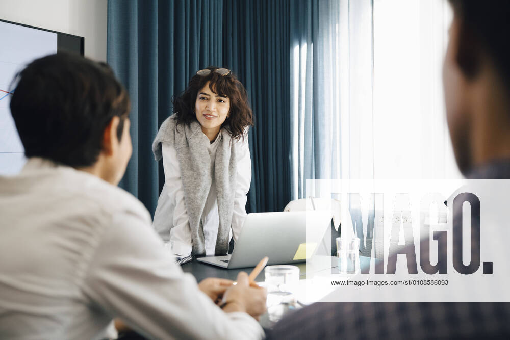 Smiling businesswoman planning strategy with male colleagues in board room during meeting Sweden, Stockholm, model released, property released