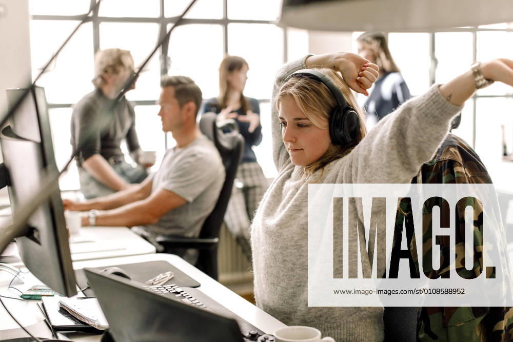 IMAGO Creative: Internationaler Frauentag, Gender Pay Gap, Frauen verdienen 18 Prozent weniger Female entrepreneur stretching while looking at computer in office Sweden, Stockholm, model released, property released