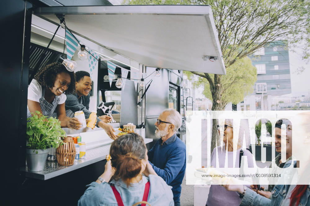 IMAGO Creative, Urban Lifestyle Smiling male and female customers talking to food truck owners in city Sweden, Stockholm, model released, property released