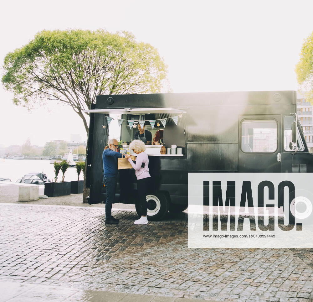 Owner talking to senior customers while standing in commercial land vehicle Sweden, Stockholm, model released, property released