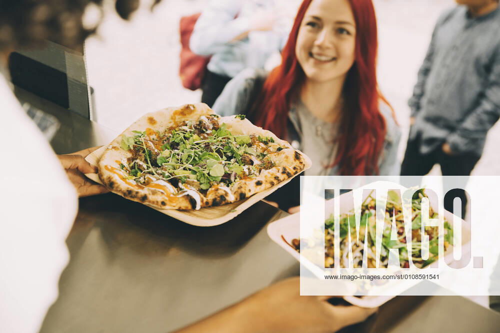 IMAGO Creative: Kreative Renaissance -- der junge Entrepreneur Female assistant giving food plate to smiling female customer in city Sweden, Stockholm, model released, property released