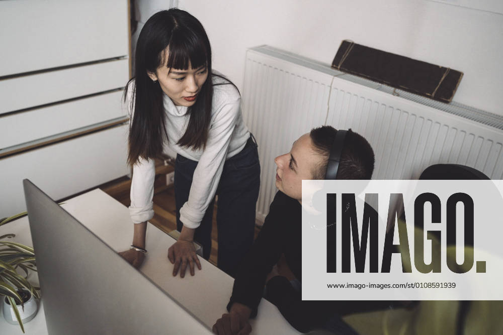 IMAGO Creative, Internationaler Frauenmonat, Entrepreneurinnen Businesswomen talking while working on computer at workplace Germany, Berlin, model released, property released