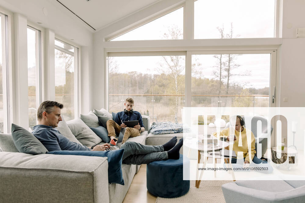 IMAGO Creative: Jahreszeit Winter, Couching Father and children using wireless technology at home Sweden, Stockholm, model released, property released