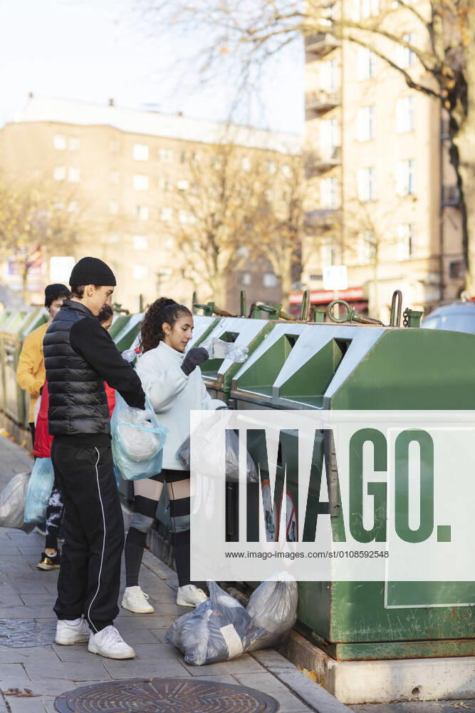 IMAGO Creative: Nächste Generation, Sozial- und klimabewusst Young male and female environmentalists throwing waste in garbage can Sweden, Stockholm, model released